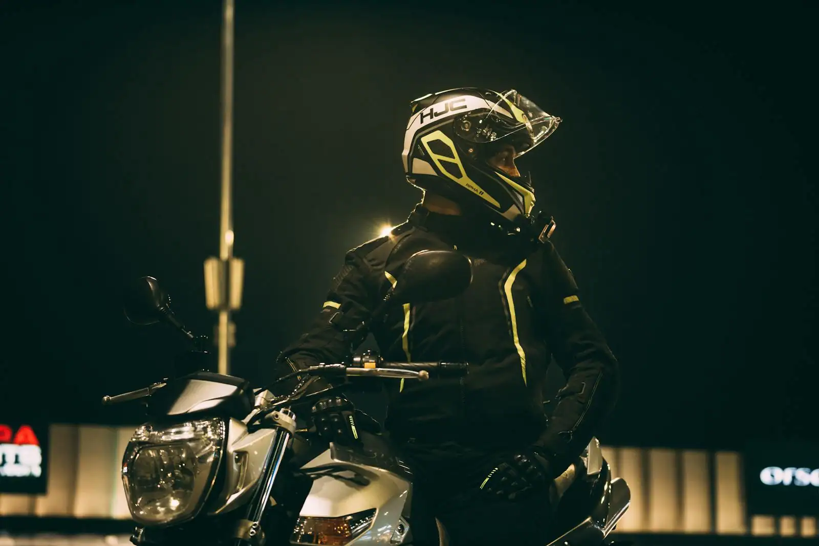 Motard équipé d'un casque, d'un blouson et de gants posant près de sa moto