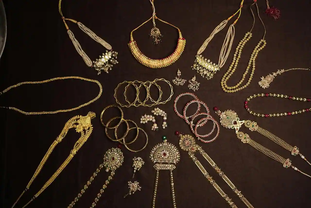 Bijoux dorés superposés : créoles, chaînes fines et collier à maillons sur fond clair
