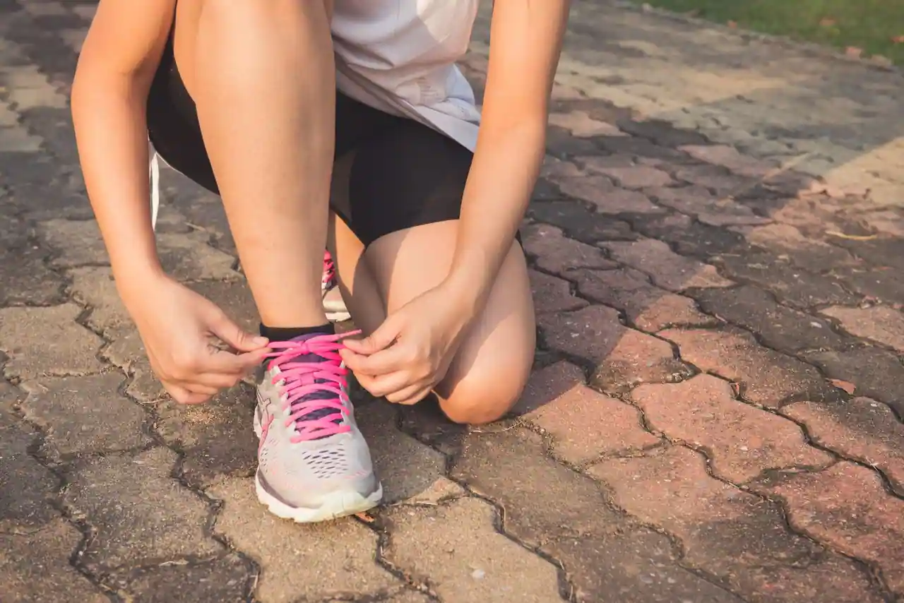 Personne en tenue de sport laçant ses baskets avant une séance, lumière du matin