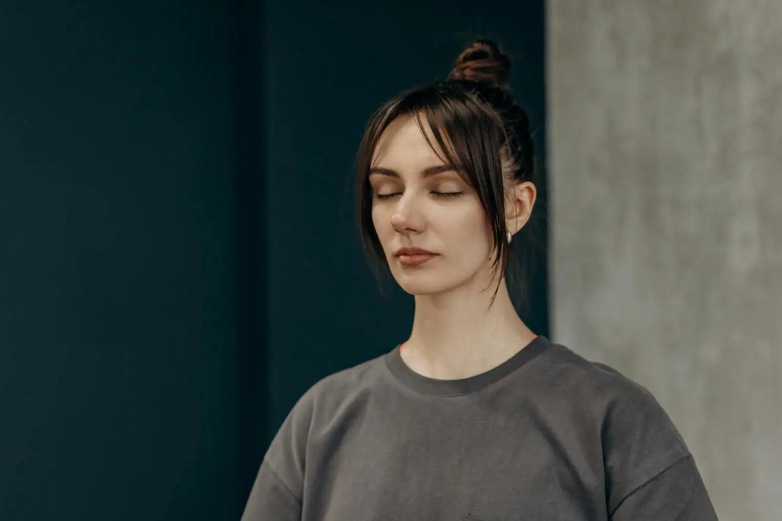 Personne assise en posture de méditation, les yeux fermés, dans une pièce calme et lumineuse
