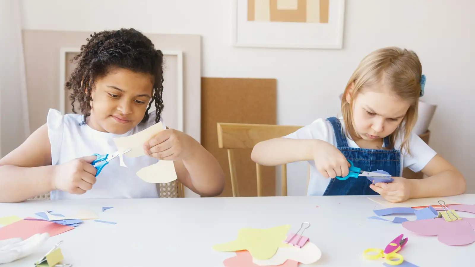 Deux jeunes enfants découpent du papier de couleur avec des ciseaux lors d'une activité manuelle