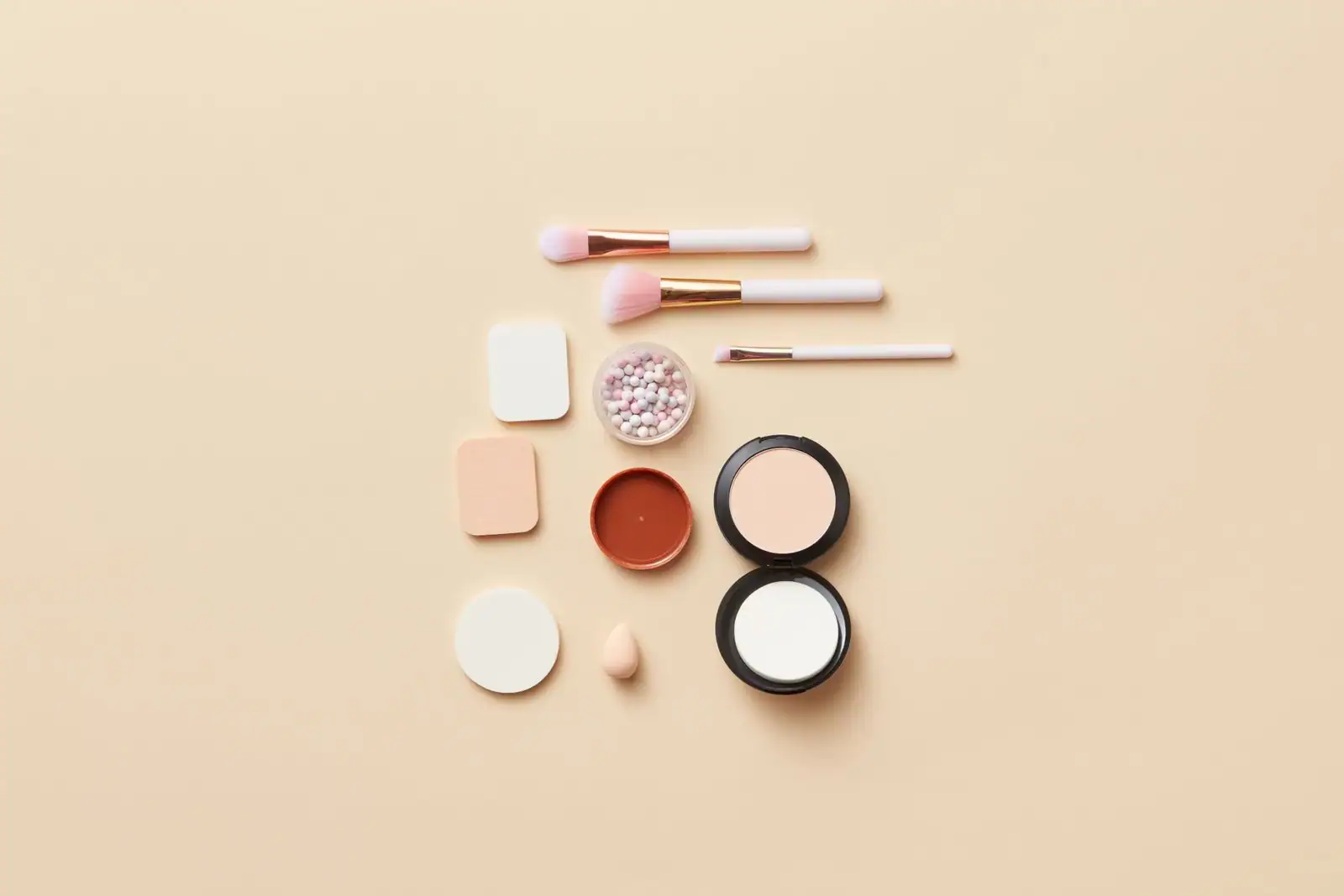 Produits de maquillage et de soin disposés à plat sur un fond beige