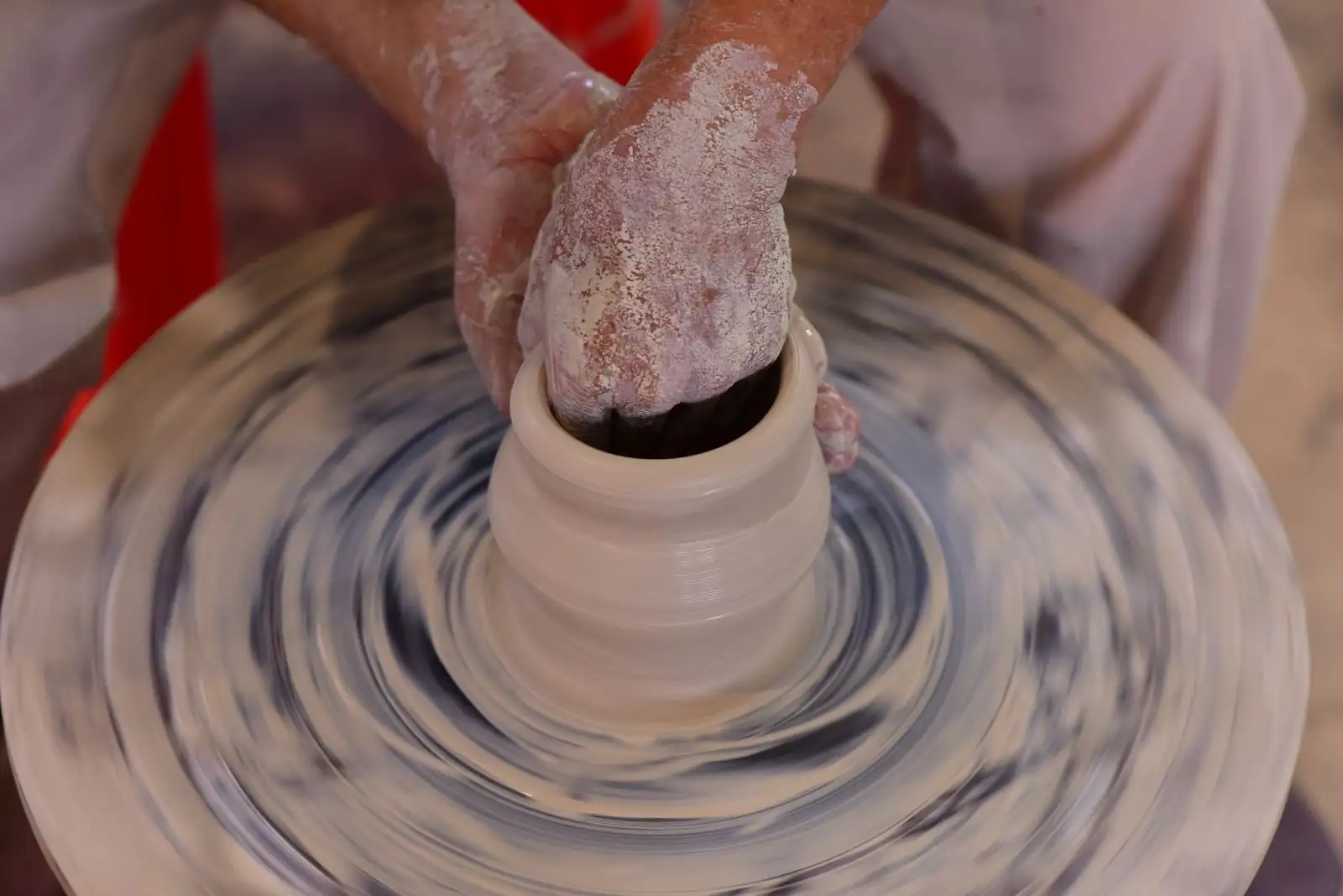 Mains façonnant une pièce d'argile sur un tour de potier dans un atelier de céramique