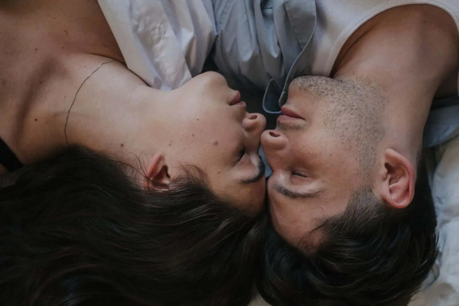 Un homme et une femme allongés face à face, nez contre nez, dans un moment d'intimité.