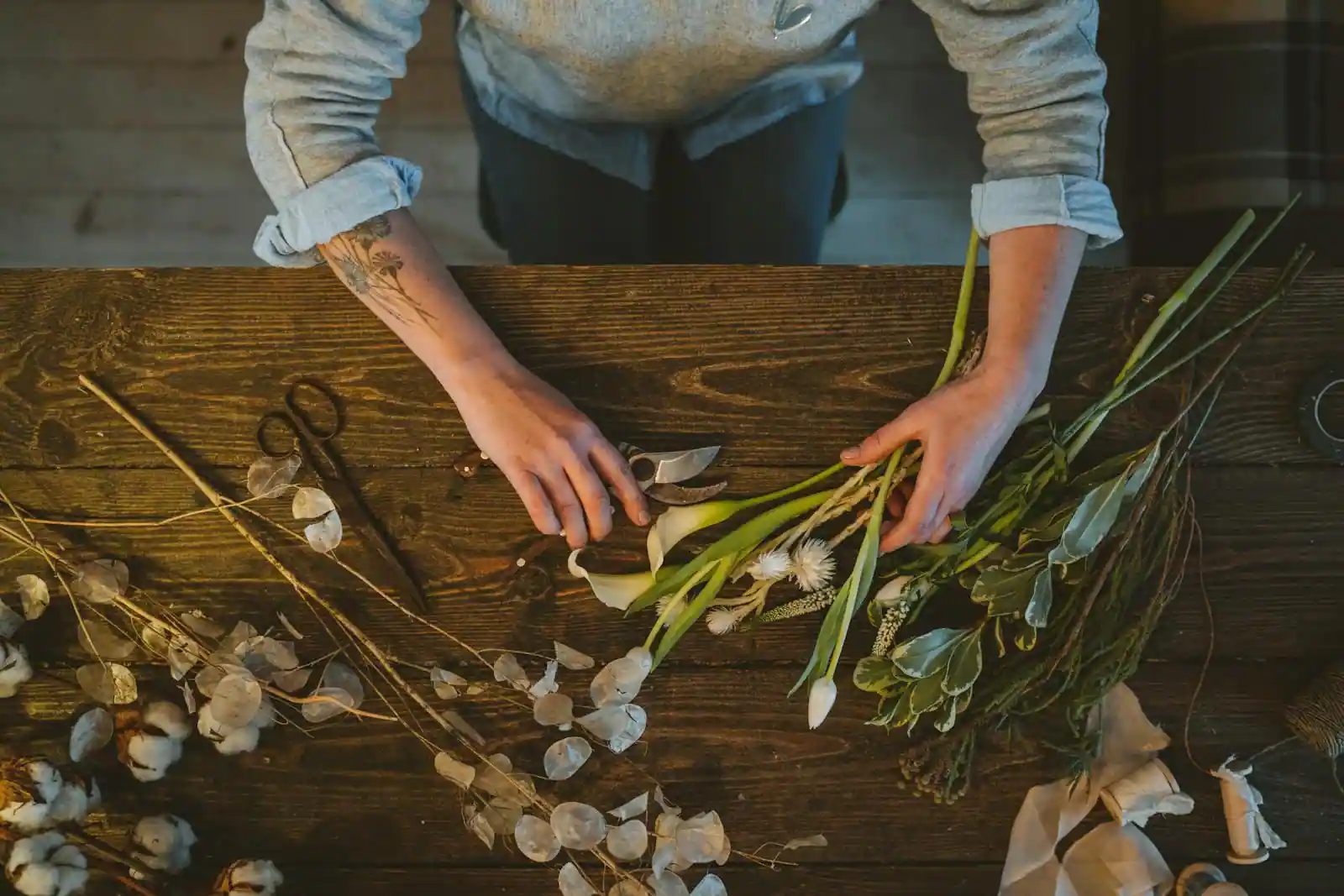 Personne installée à une table en bois, absorbée par une activité de loisir créatif