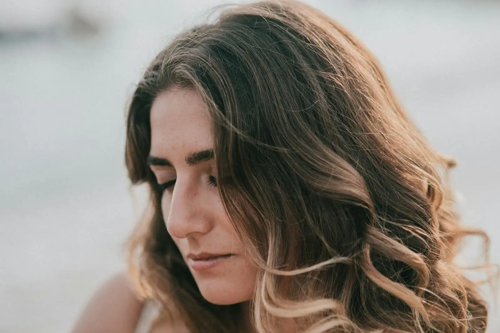 Jeune femme aux longs cheveux blonds lumineux, vue de profil dans une lumière naturelle douce.