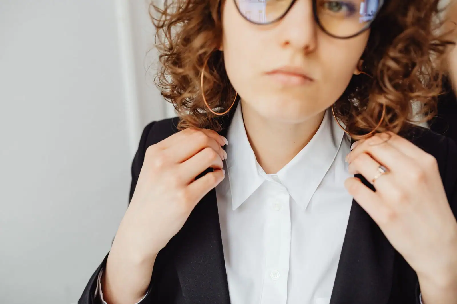 Femme ajustant un blazer foncé sur une chemise blanche, tenue sombre et sobre adaptée à un enterrement