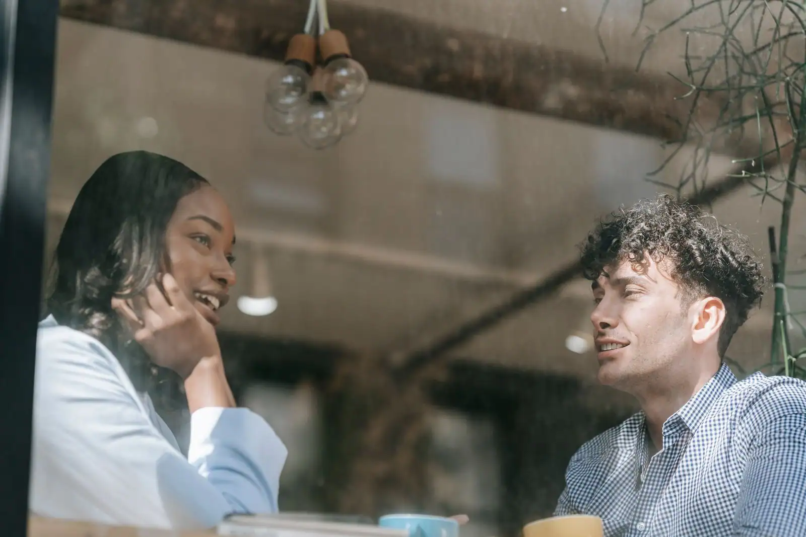 Un homme et une femme en pleine conversation complice dans un café, regards souriants