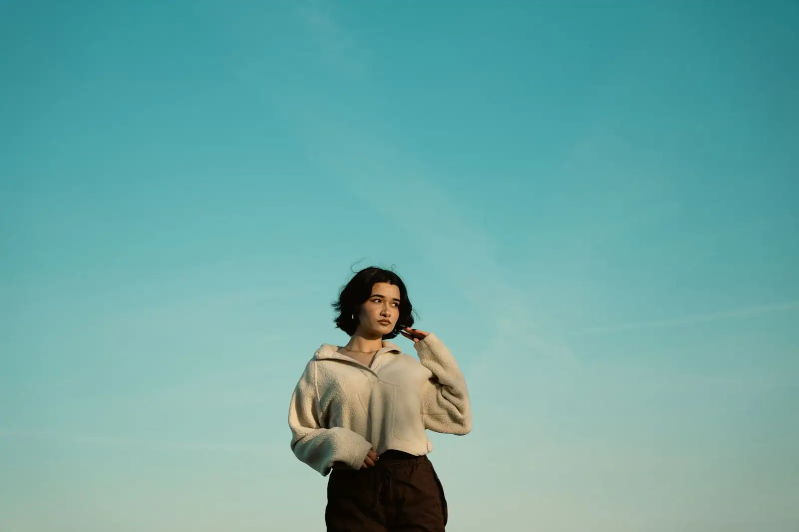 Femme au regard assuré et à la posture calme, dans une lumière naturelle, évoquant la confiance en soi.
