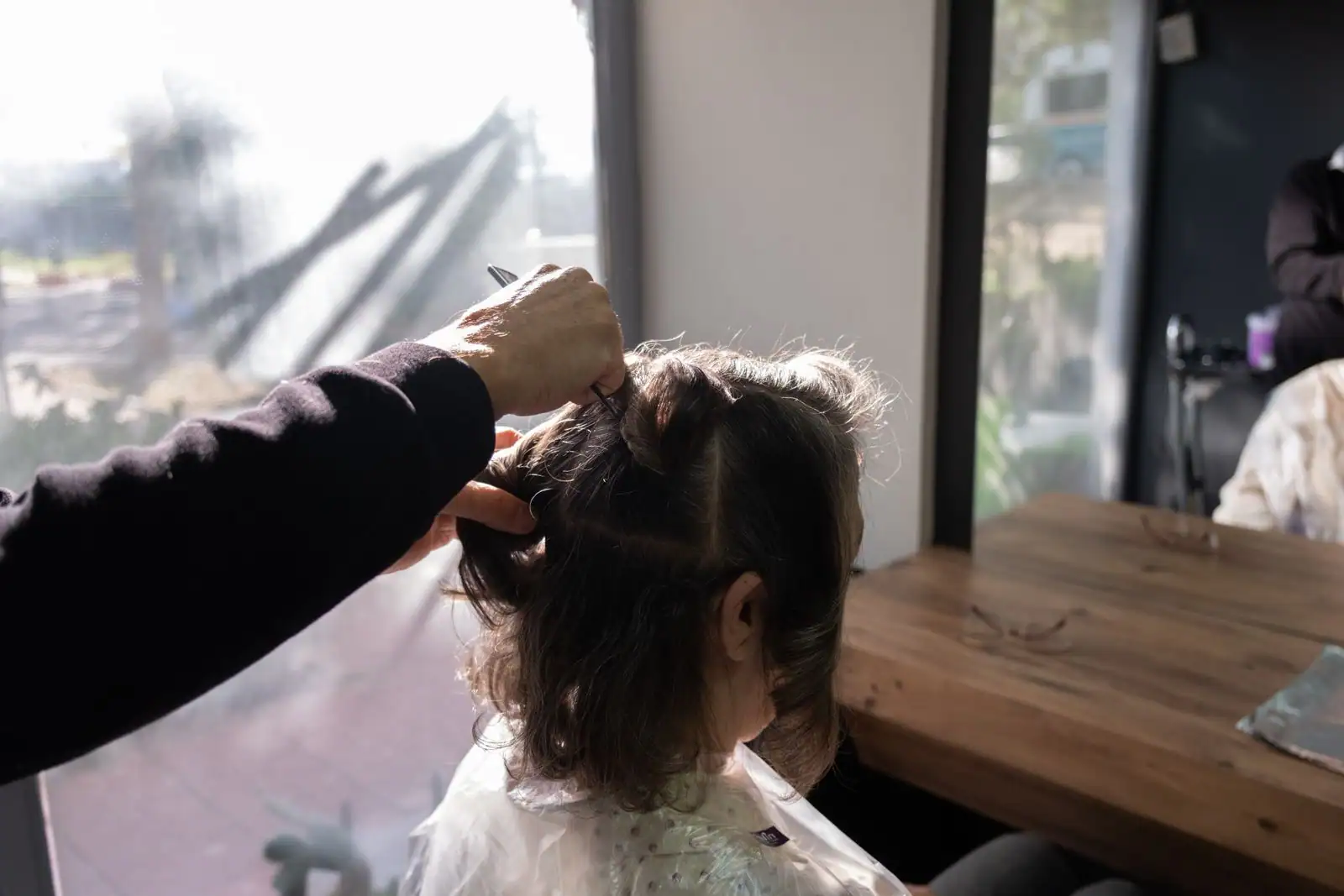 Séance de coupe chez le coiffeur : une femme se fait tailler les cheveux aux ciseaux dans un salon lumineux