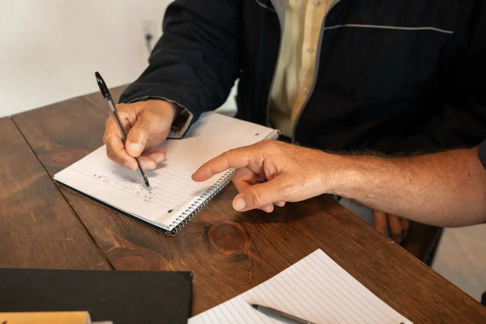 Adulte concentré prenant des notes dans un carnet pendant une formation, stylo en main