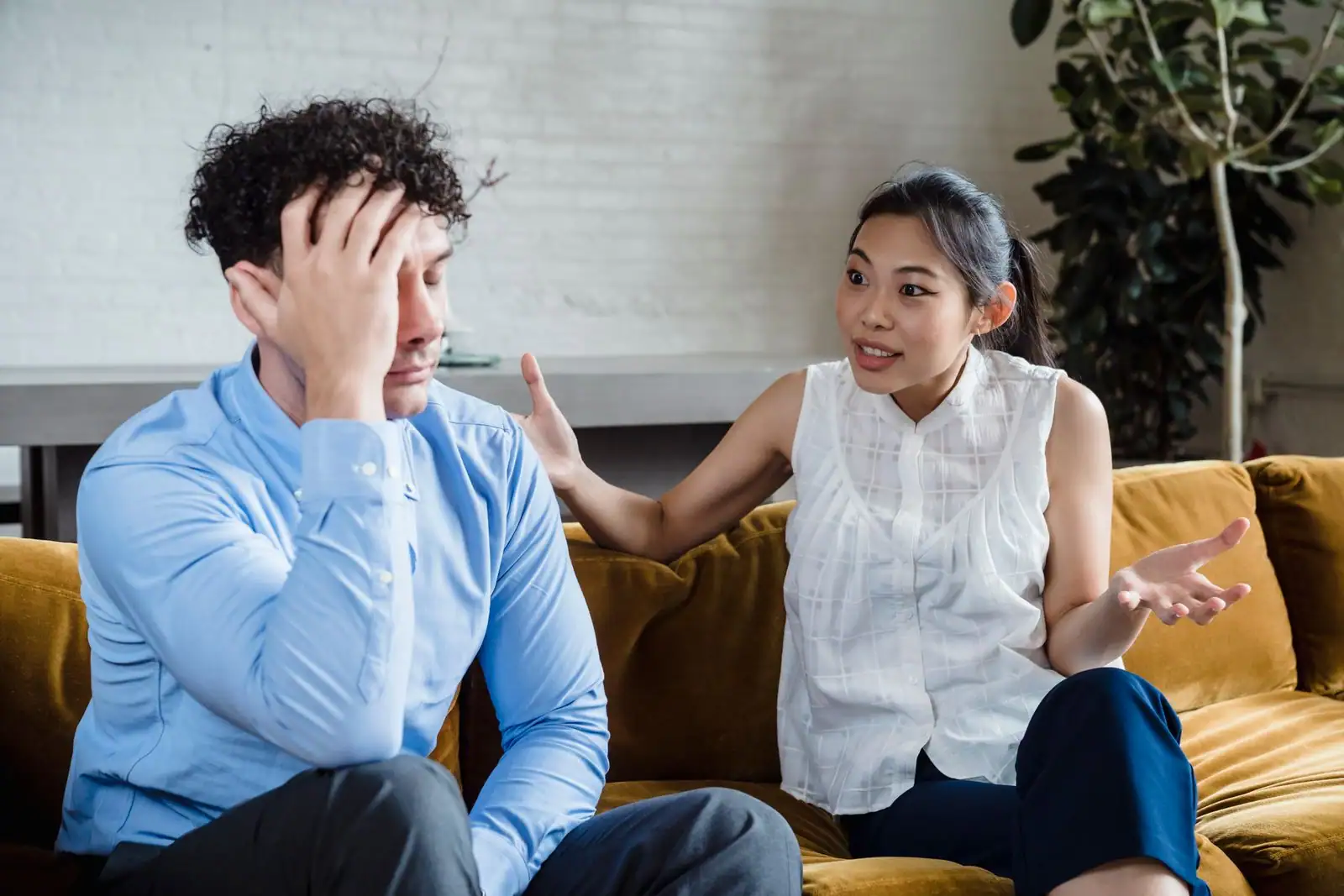 Un couple assis sur un canapé, en pleine tension pendant une discussion animée à la maison.