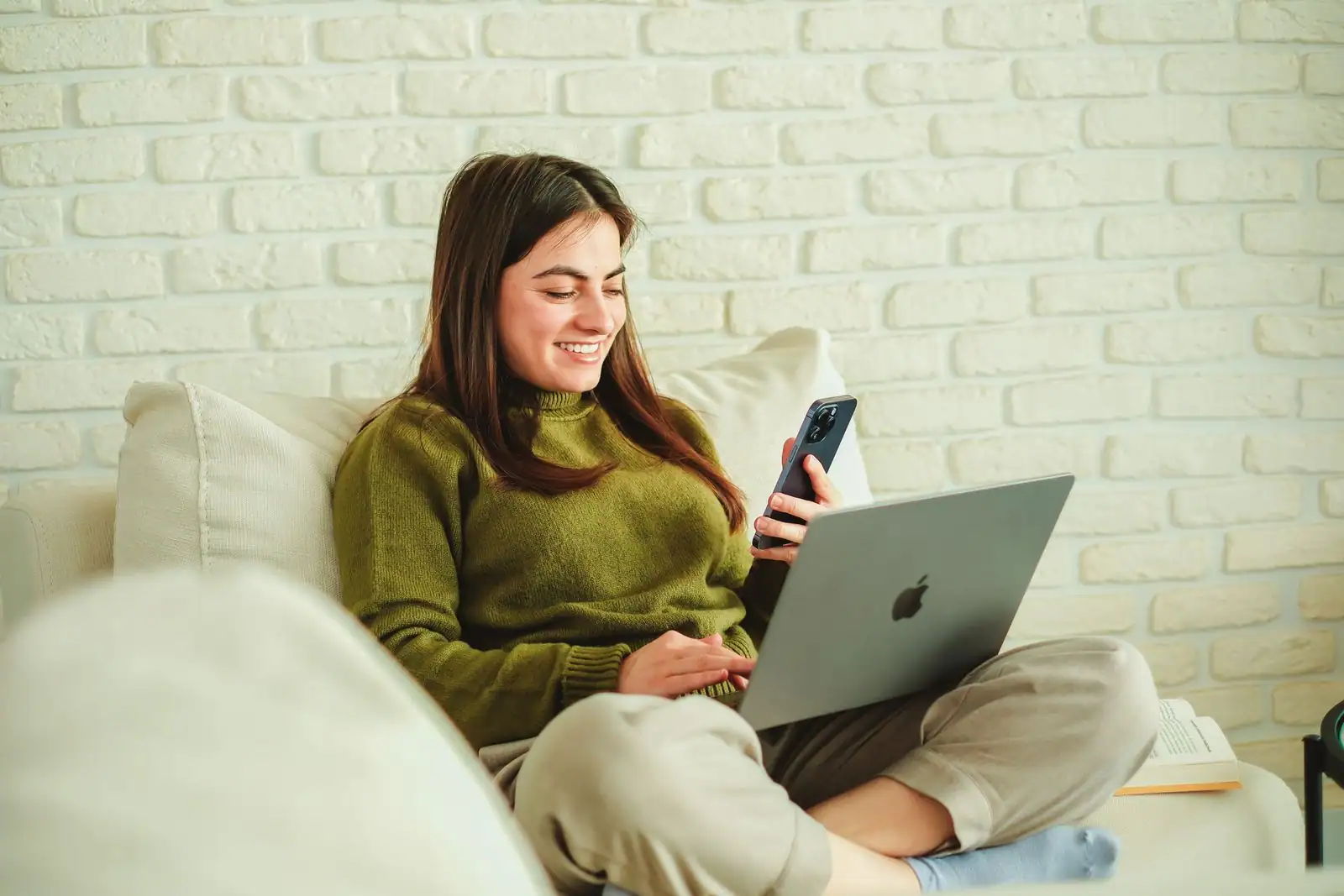 Une jeune femme souriante, smartphone à la main, en train d’écrire un message dans une ambiance détendue.