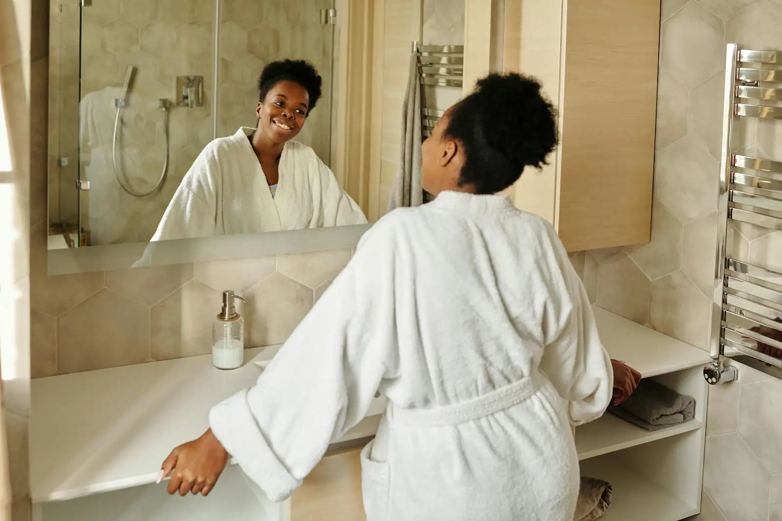 Femme sereine souriant doucement à son reflet dans un miroir, lumière naturelle