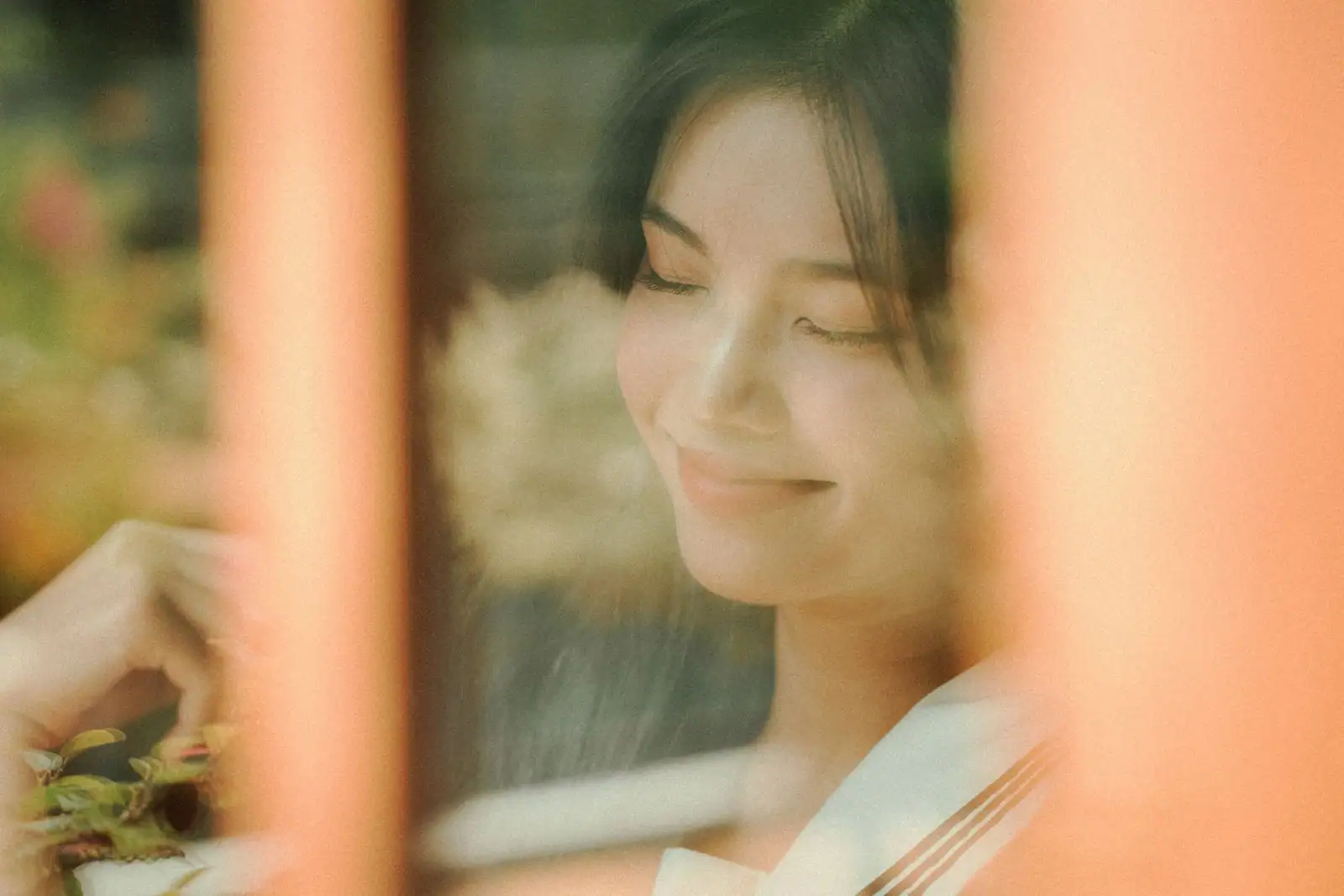 Jeune femme au visage apaisé, les yeux clos et un léger sourire, derrière une vitre baignée de lumière douce