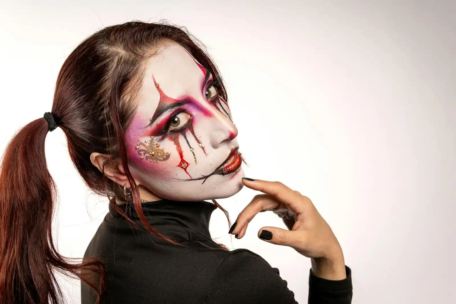 Portrait artistique d'un visage peint en blanc au maquillage de clown dramatique rouge et noir