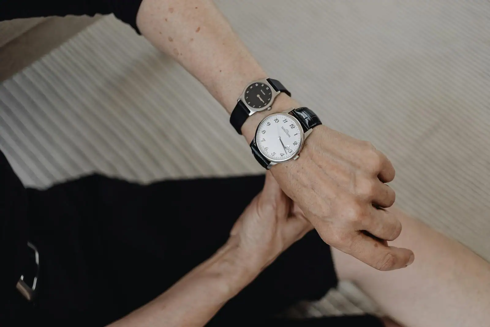 Poignet féminin portant une montre analogique en acier au cadran clair, photographiée de près en lumière naturelle.