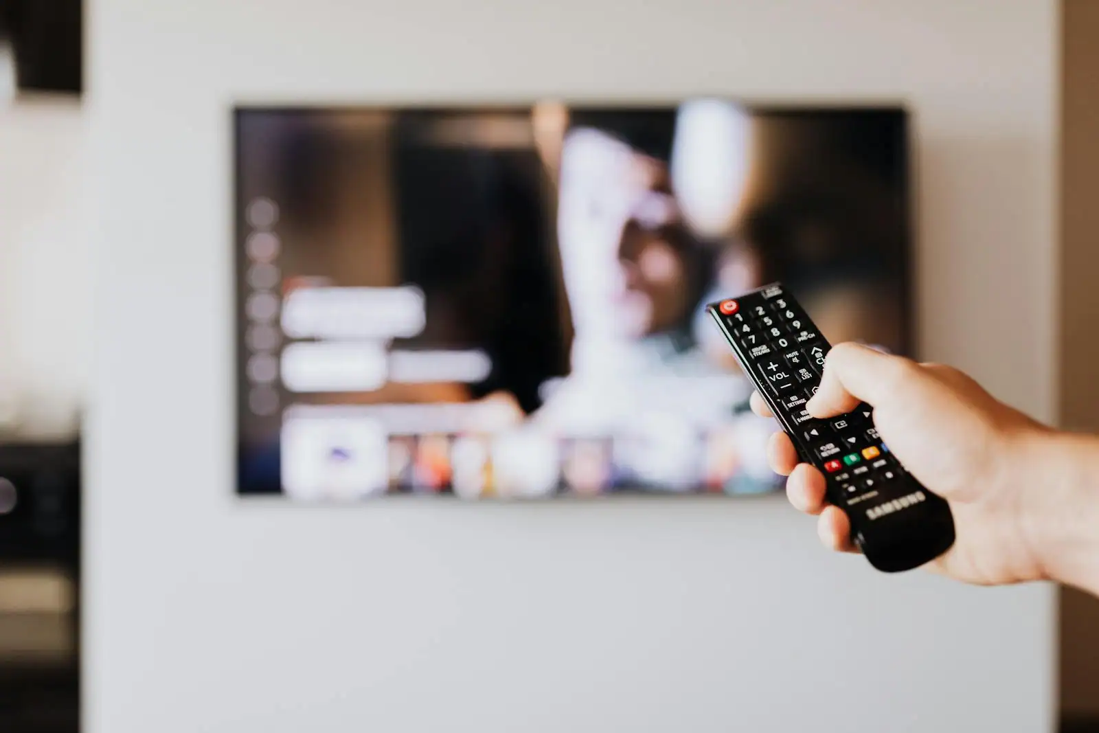 Téléviseur diffusant une série en streaming, télécommande tenue au premier plan