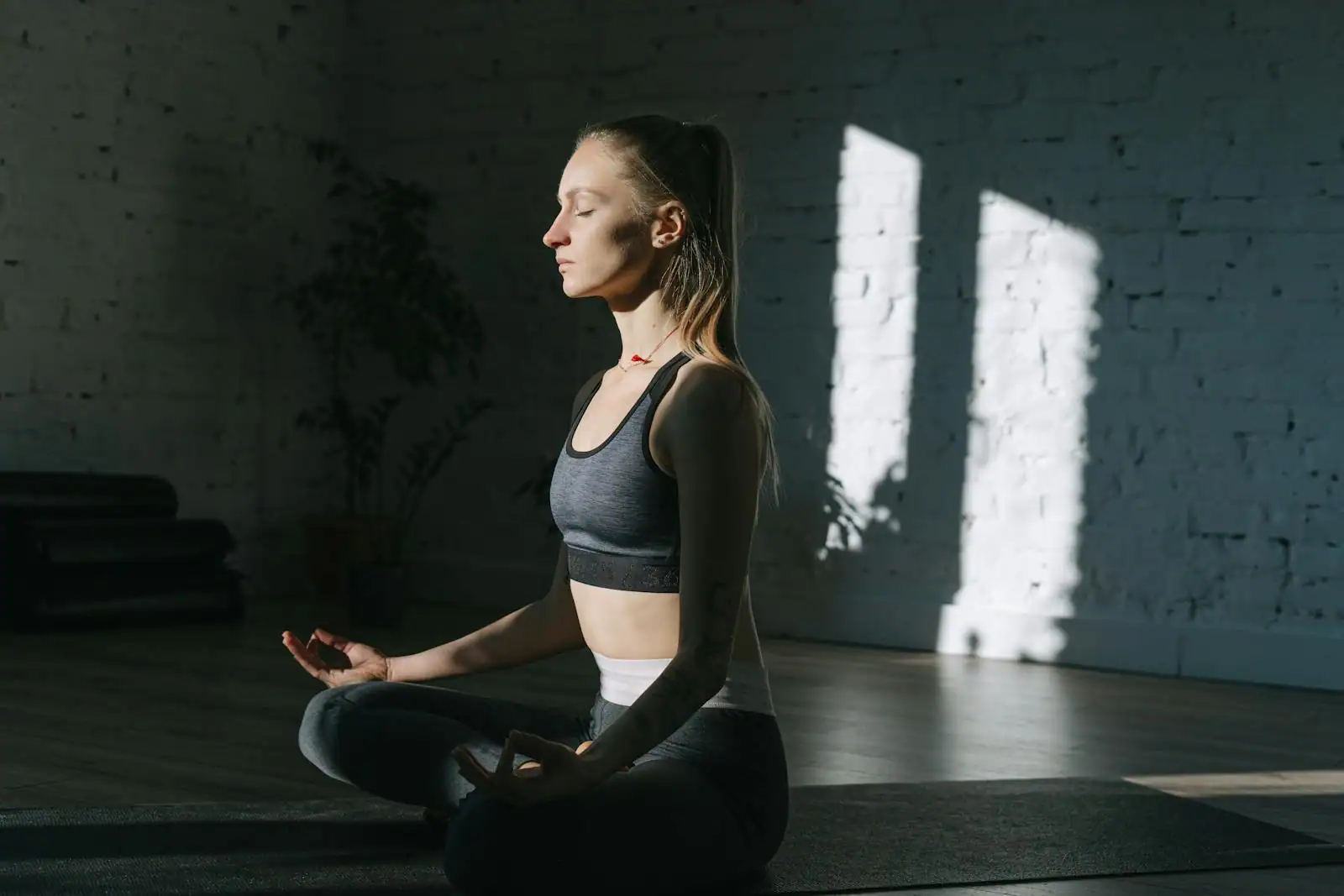 Femme assise en méditation, les yeux fermés, dans une lumière naturelle douce et apaisée.