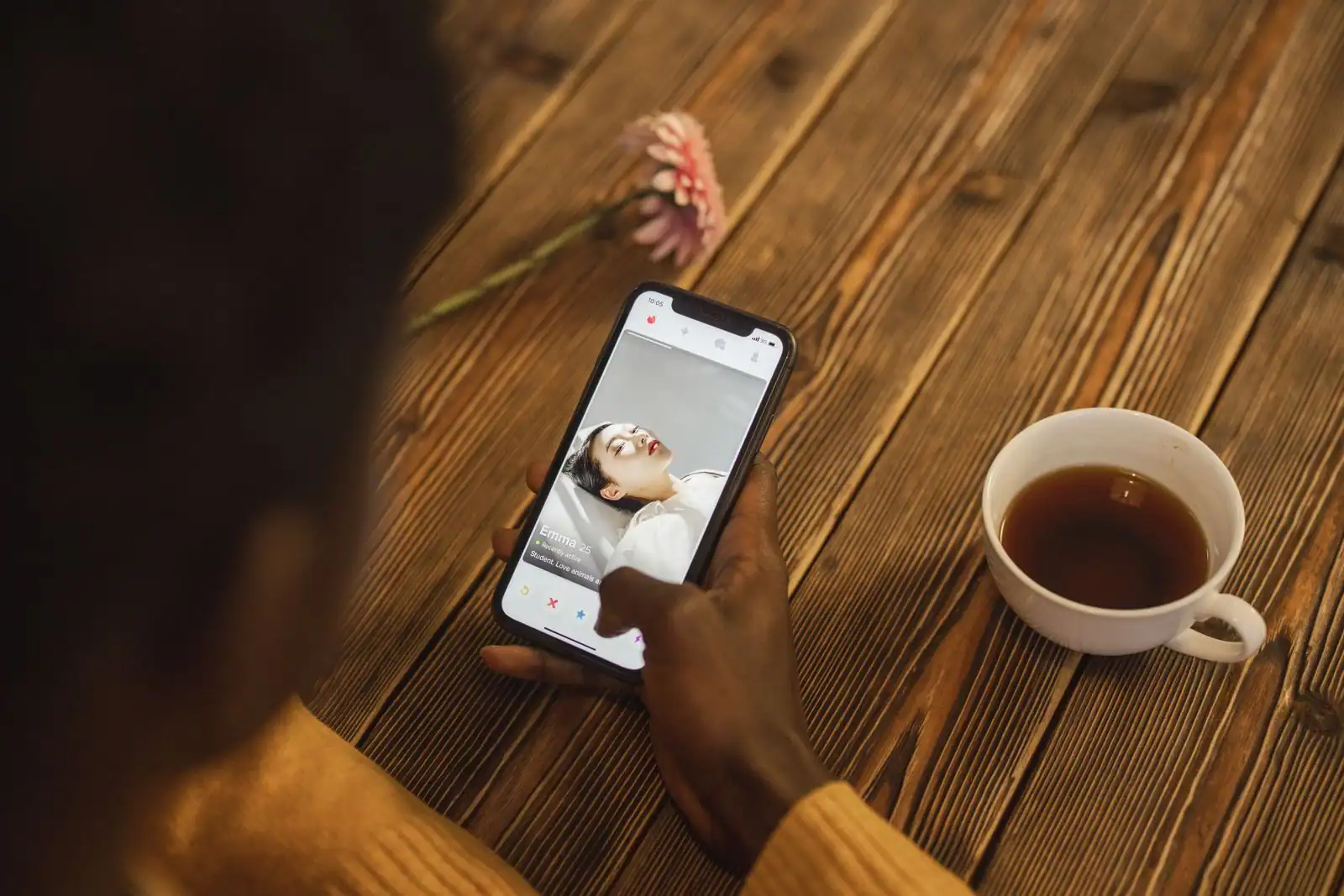Personne consultant un profil sur une application de rencontre depuis son smartphone, posée sur une table en bois