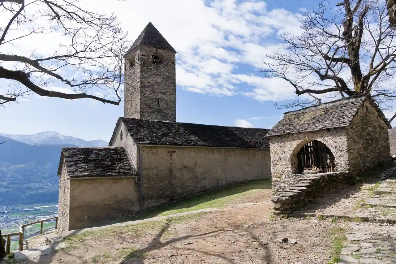 Une vieille église de village en pierre, surmontée de son clocher, dans la campagne.