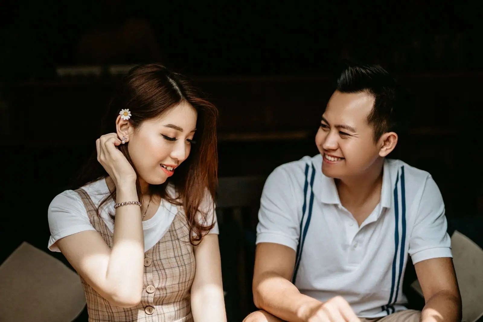 Couple complice qui flirte en se souriant, assis l'un près de l'autre