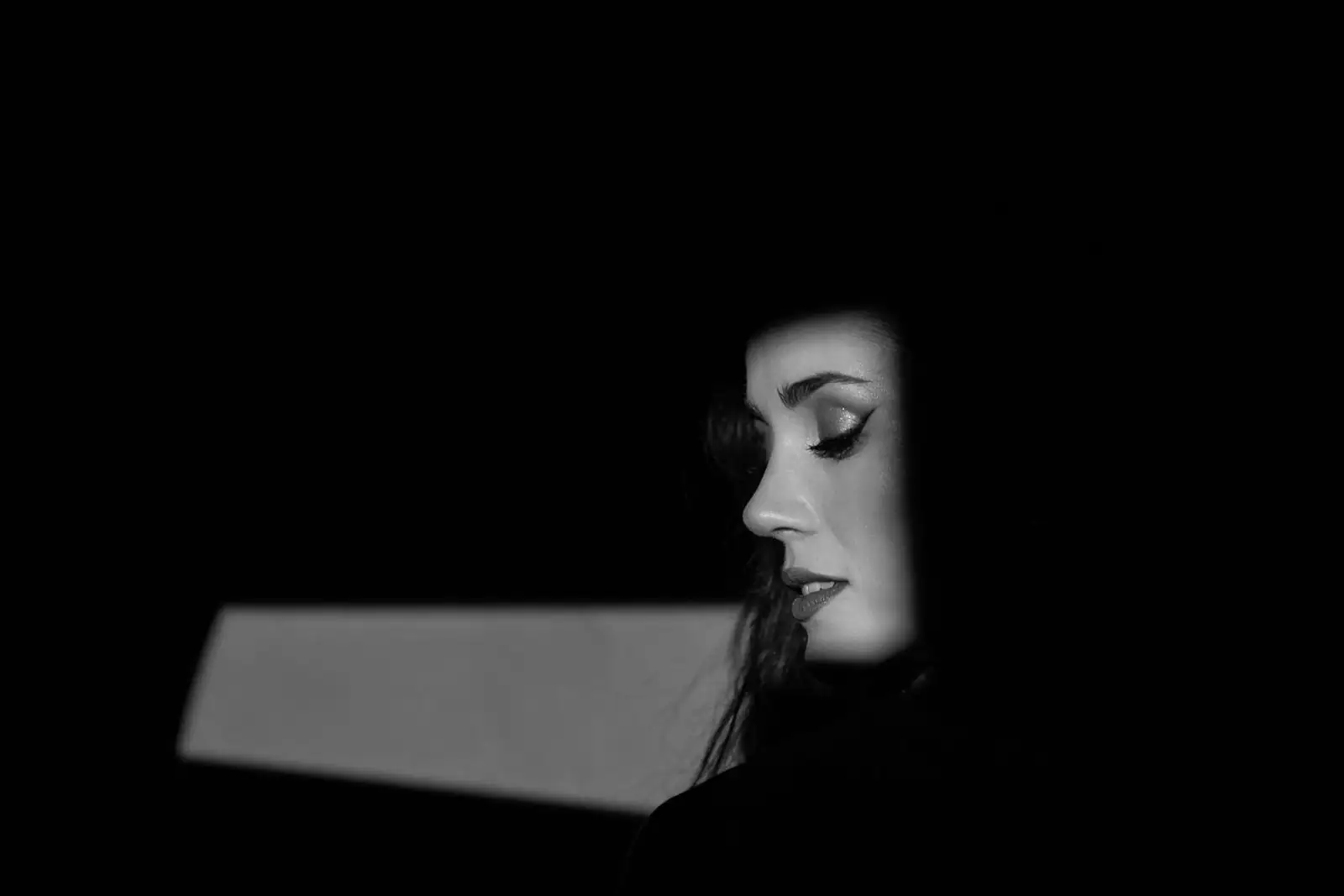 Portrait d'une femme élégante au regard assuré et mystérieux, en lumière douce, évoquant un charme posé.