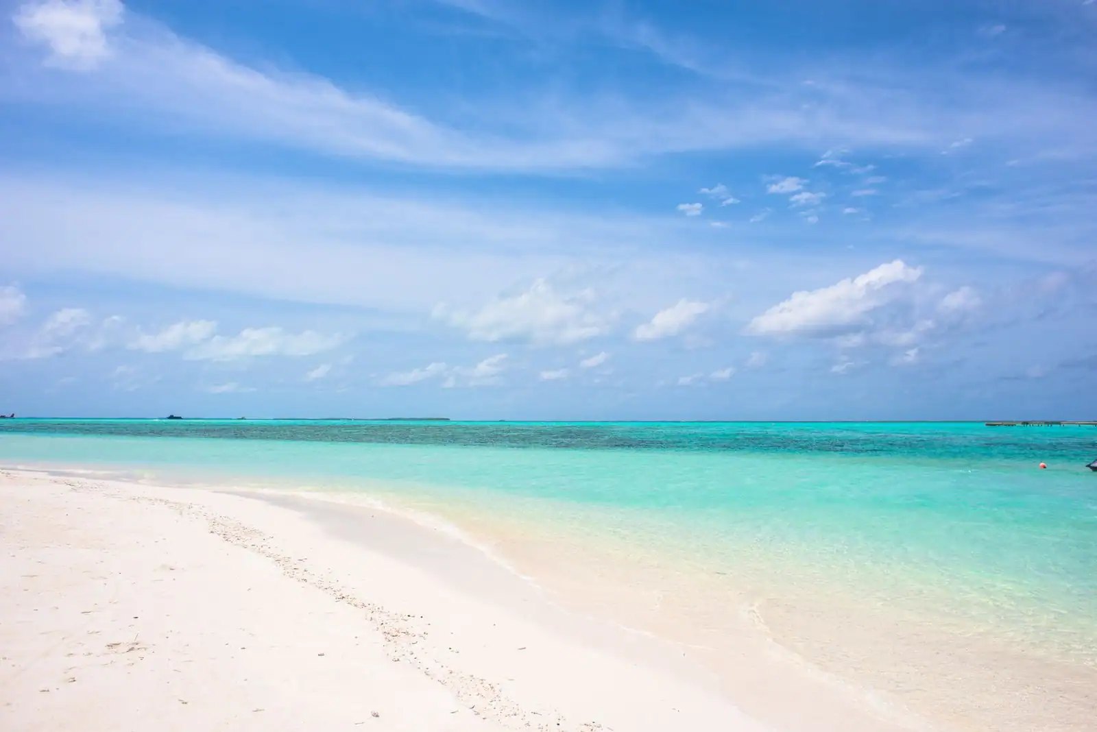 Plage tropicale déserte aux eaux turquoise et au sable blanc sous un ciel bleu