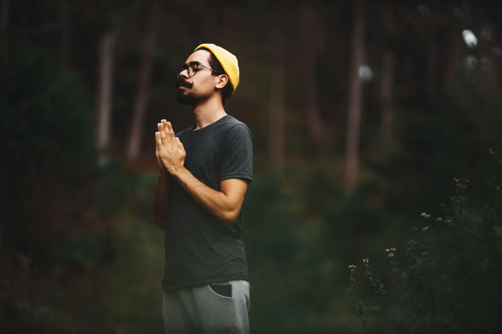 Homme aux mains jointes en pleine méditation dans la nature, image d’introspection et de vie intérieure