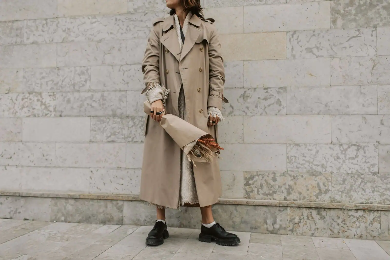 Femme en trench beige sur une tenue claire, chaussures derbies noires, allure sobre et élégante.