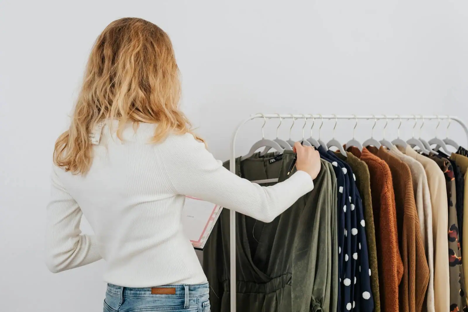 Jeune femme parcourant des vêtements sur des portants dans une boutique de prêt-à-porter abordable