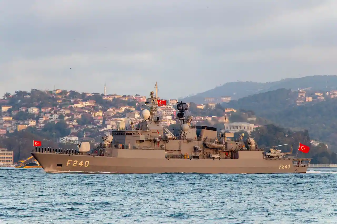 Bâtiment de guerre gris de la marine naviguant au large sous un ciel gris couvert.
