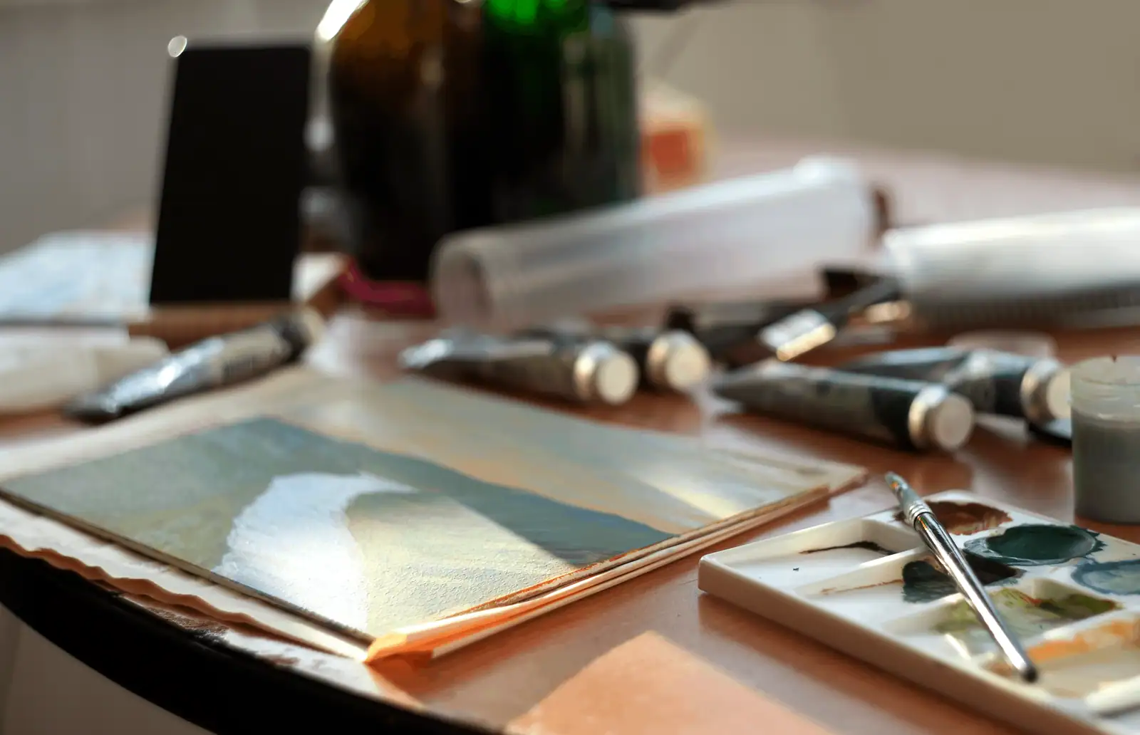Table avec plusieurs loisirs réunis : carnet de dessin, pinceaux, pelote de laine et appareil photo