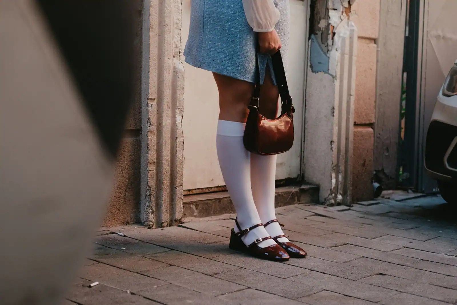 Tenue de ville soignée : jupe, chaussettes hautes, escarpins en cuir et sac, pour un look du quotidien bien composé.