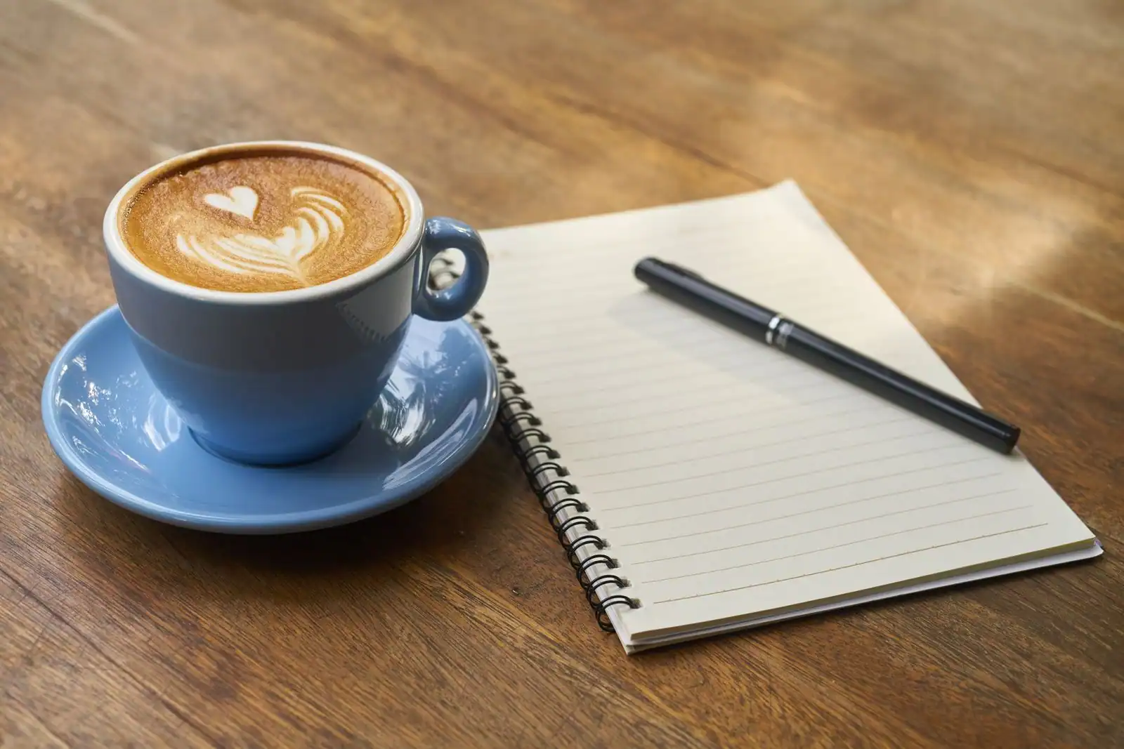 Tasse de café et carnet posés le matin, début d'une routine quotidienne