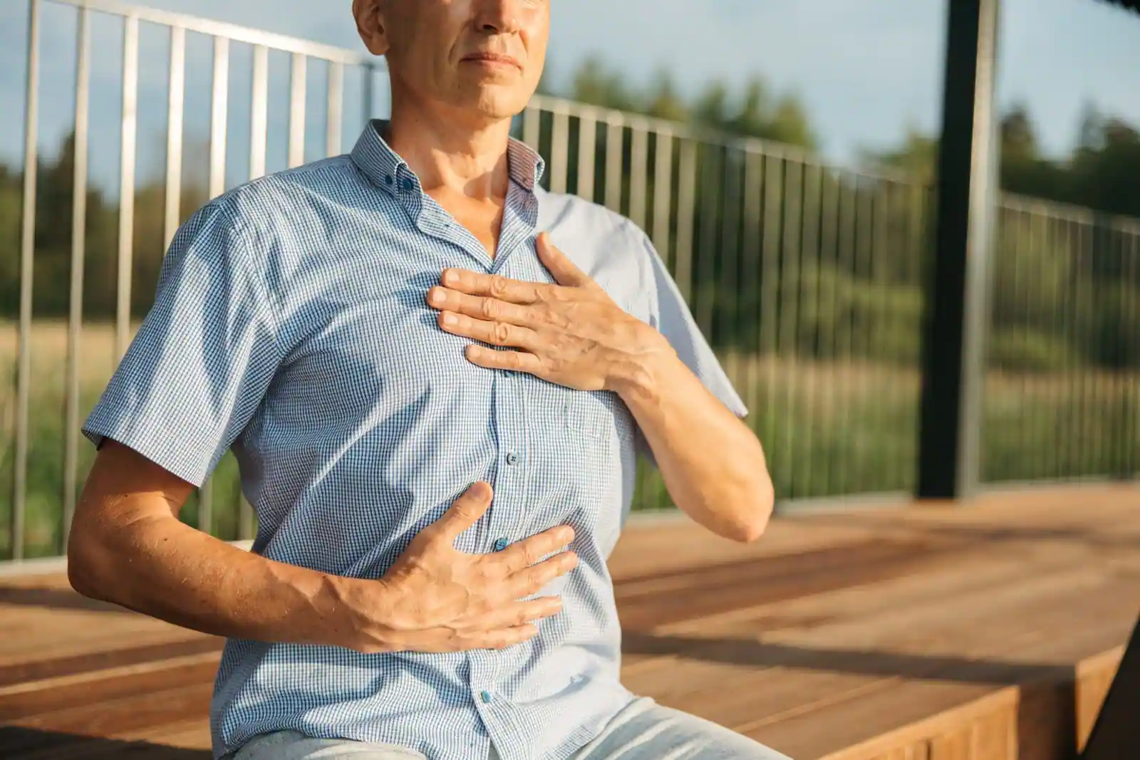 Un homme assis en extérieur pose les mains sur sa poitrine, en plein exercice de respiration