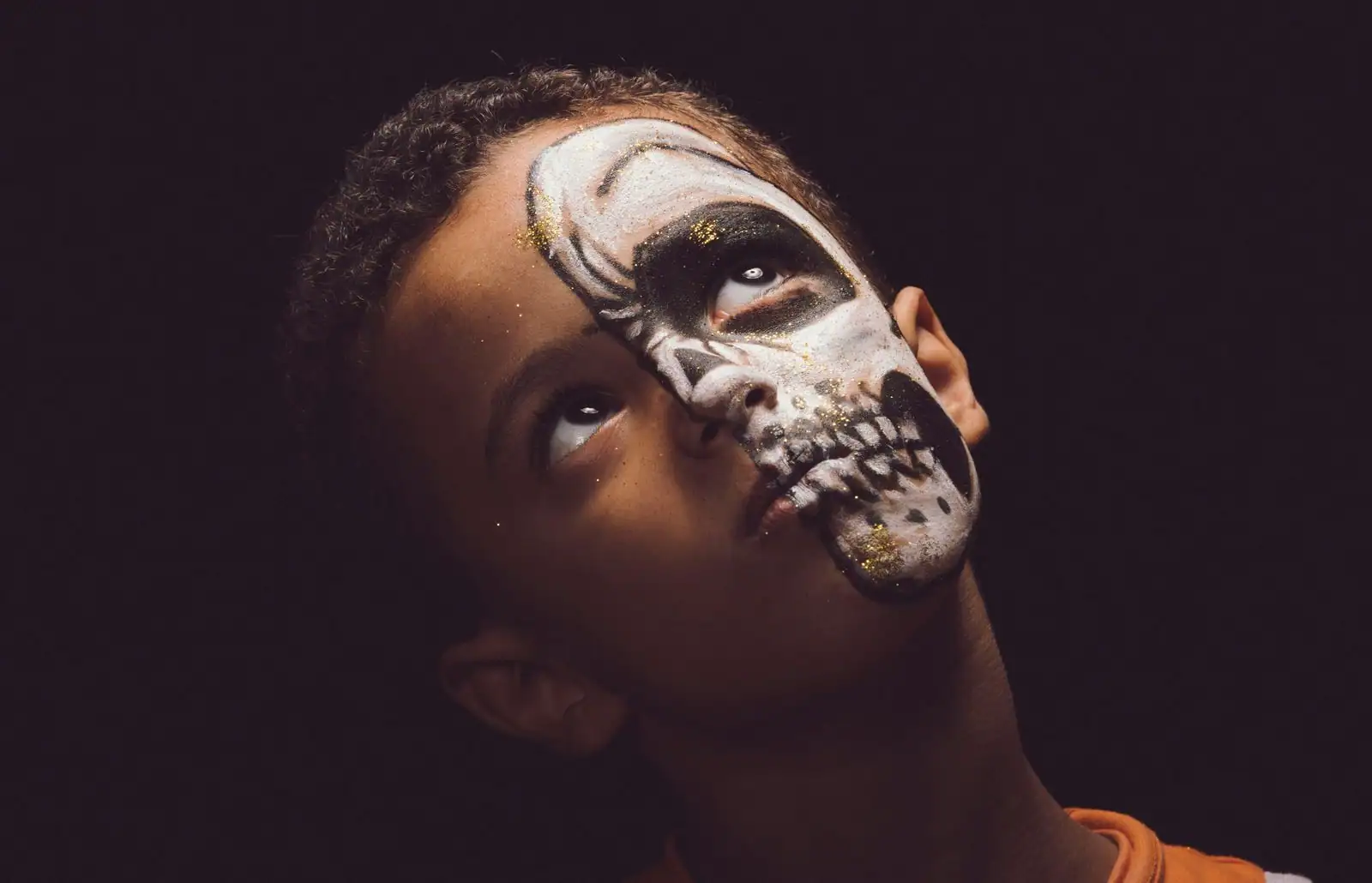 Enfant avec un maquillage noir façon masque de super-héros pour Halloween, ambiance festive.