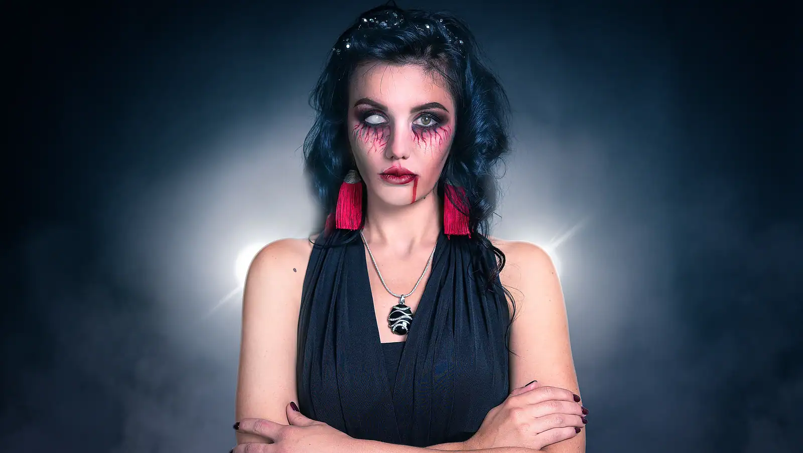 Visage maquillé en vampire, teint très pâle, regard intense et bouche sombre marquée.