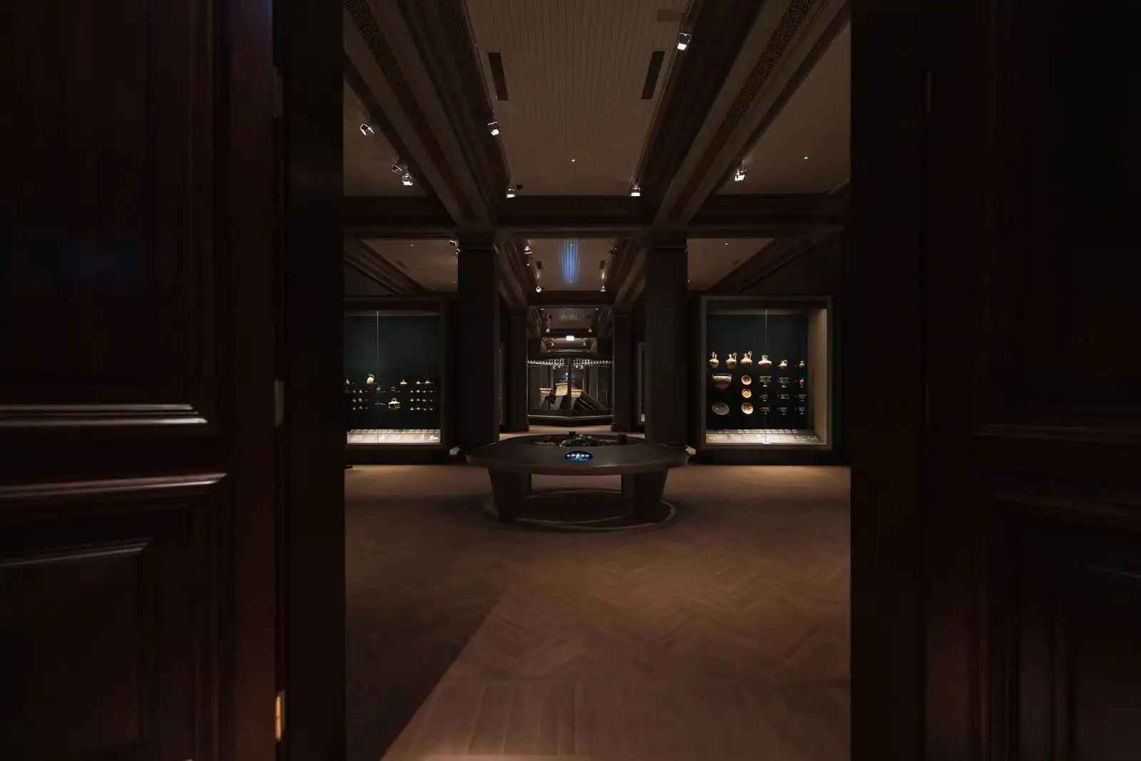 Salle d'exposition d'un musée maritime, vitrines éclairées et parquet en chevrons