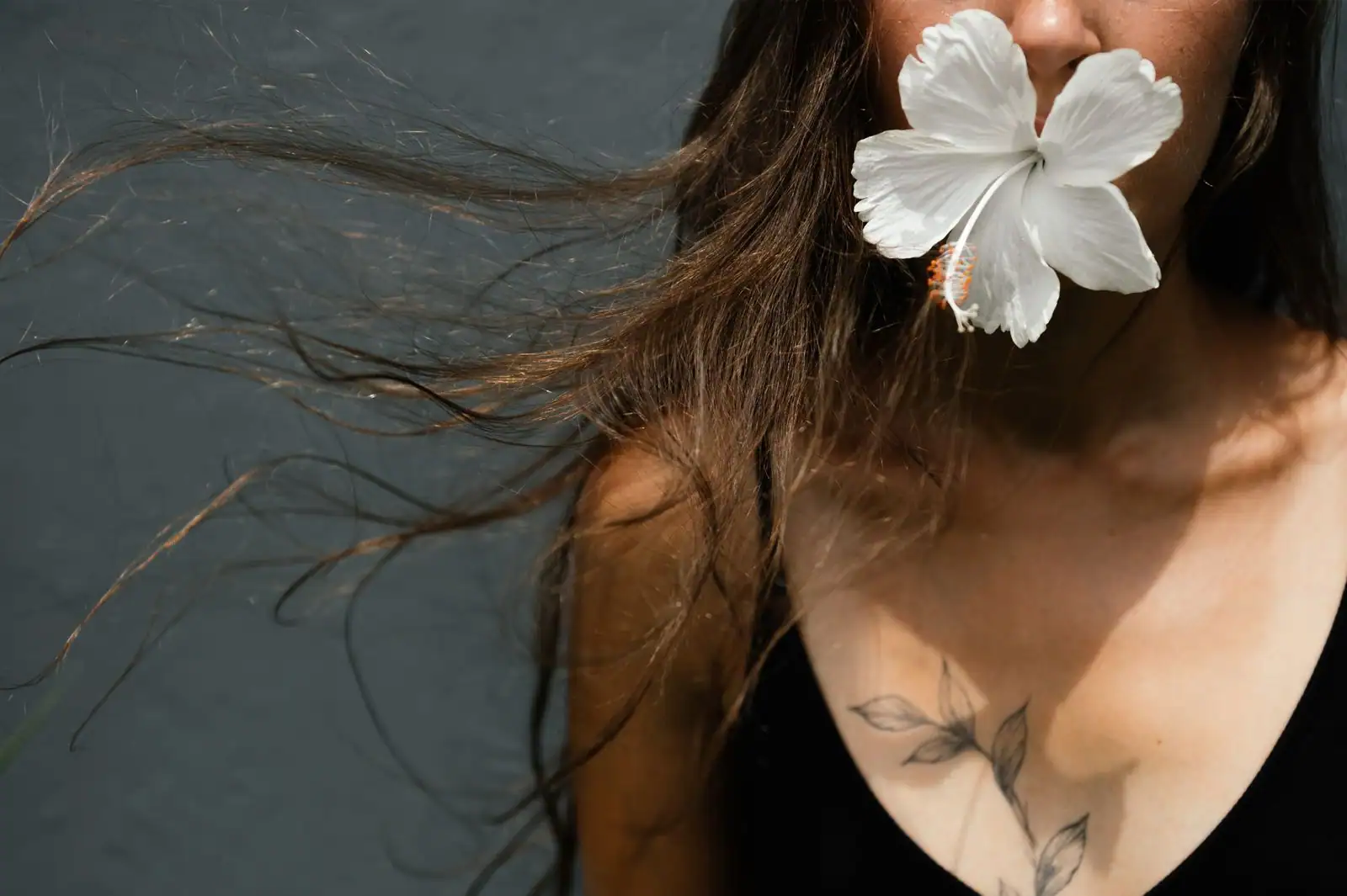 Tatouage floral discret au trait fin sur la clavicule et le haut de la poitrine d'une femme.